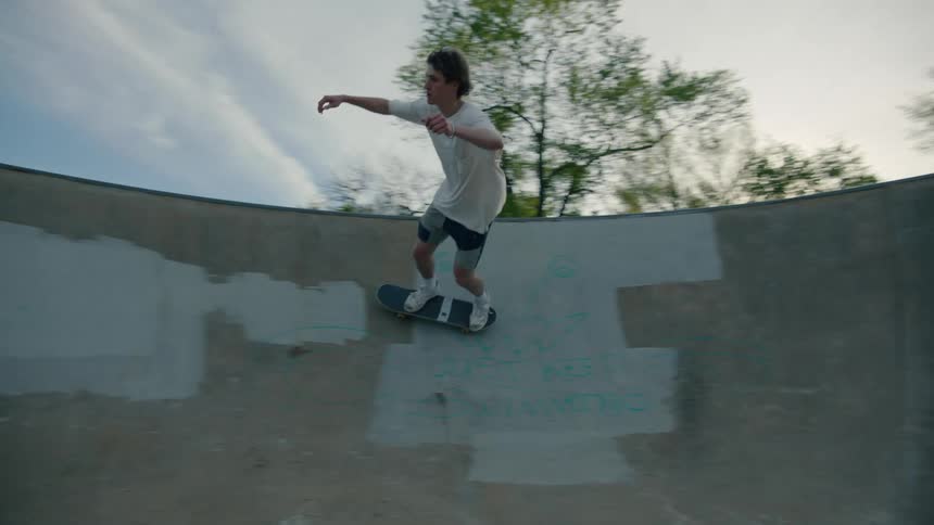 A man is skateboarding at a skateboard course in a park