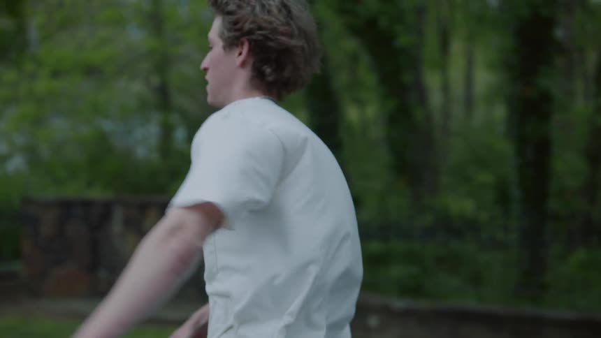 A slow motion shot of a skateboarder skating down a suburban street during the day