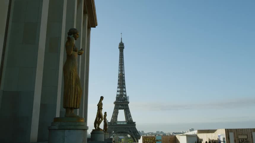 Statues stand outside of a building near the eiffel tower in paris