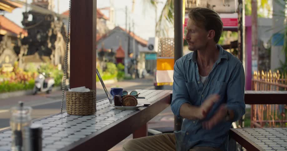Man eating breakfast sitting on a restaurant next to a street at morning