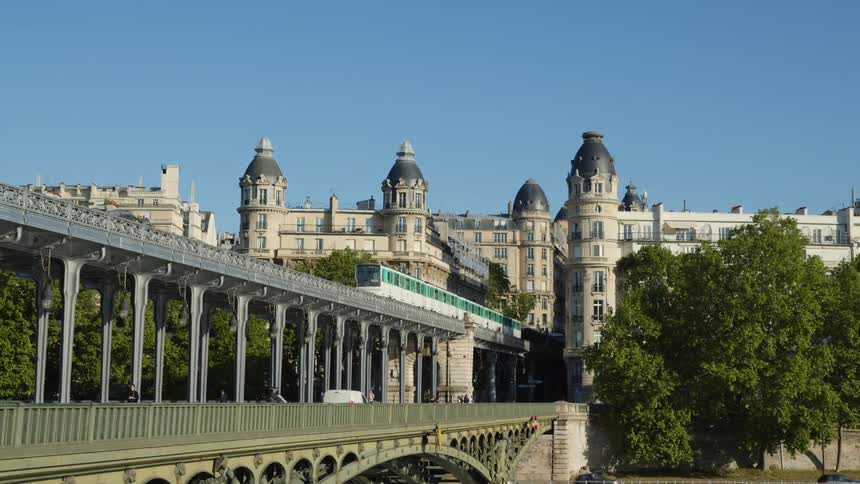 A metro train travels on the top tier of the pont de birhakeim bridge in paris