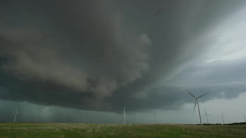 Time lapse of dark clouds swirling over a wind farm with wind turbines in Iowa