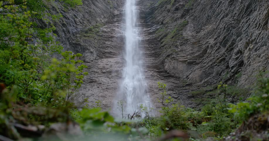 A waterfall rushes down the side of a canyon