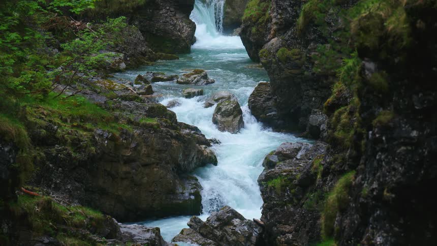 River water flows over rock and down a waterfall through a lush green landscape