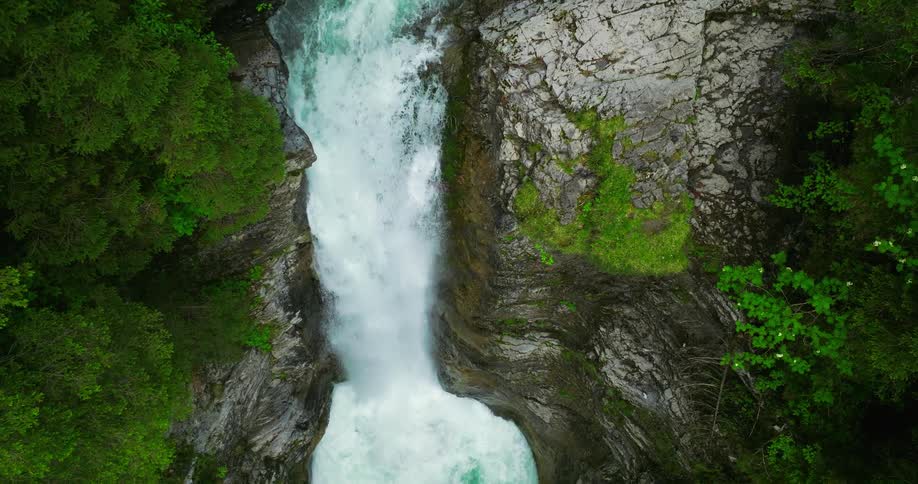 Water flows down the waterfall and splashes into the river below