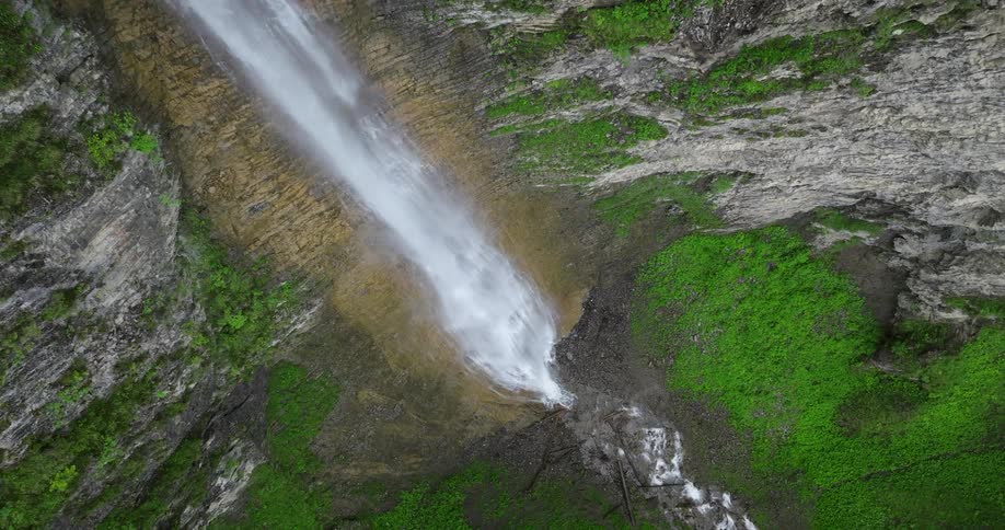 Water flows from the tall waterfall and splashes into the river below