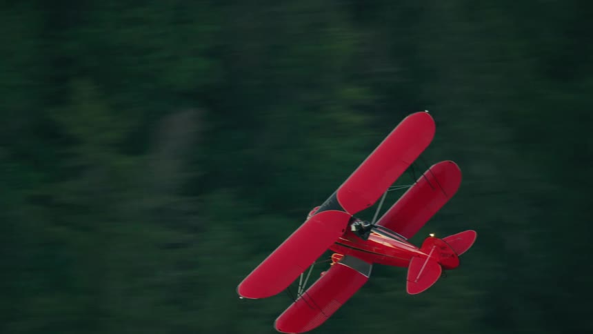 A red WACO biplane flying low setting up for a evening landing at the airport