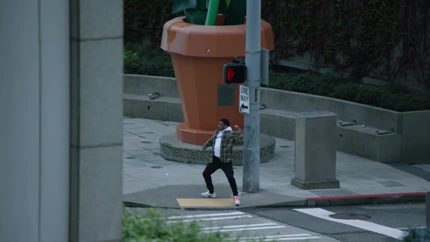 A man is standing on a street corner dancing at a crosswalk