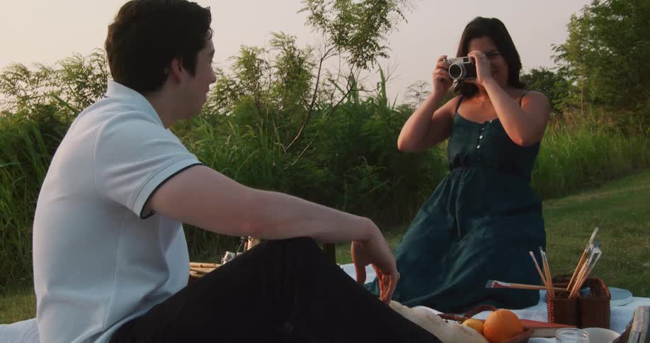 There is a couple taking a picture and having a picnic