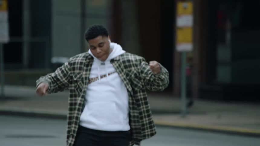 A man dances with earphones in while walking downtown