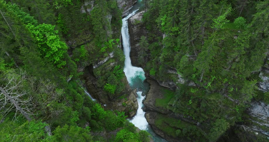 A stream of water flows down the sheer cliff splashing into the basin below