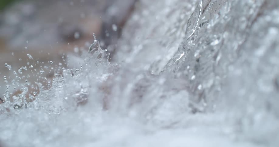 Water splashes upward and outward as a waterfall meets a river