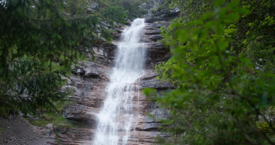 Water from a waterfall can be seen cascading down the side of a rocky cliff