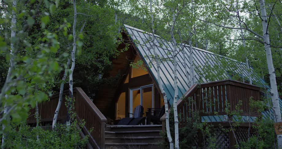 A light comes on inside an a frame cabin in the woods