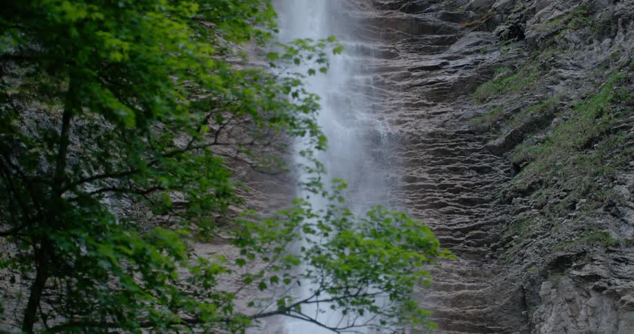 Waterfall flows down rough textured cliff