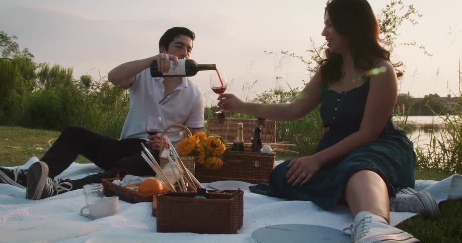 Couple is having picnic outdoors and drinking some wine together