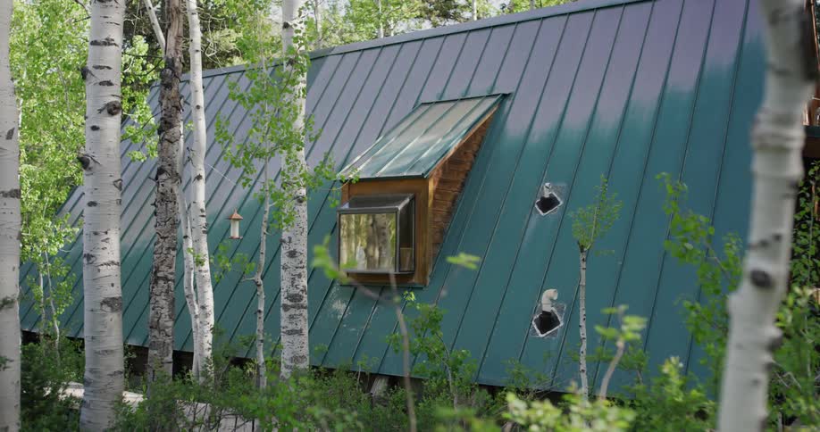 Garden window occupies center of the blue a frame roof of a home surrounded by trees