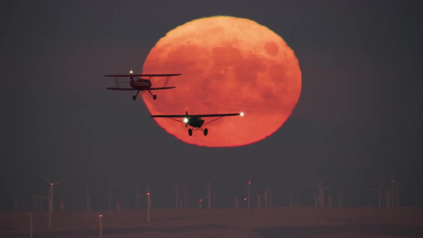 A view of two planes flying in front of the full moon