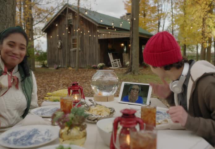 A group of family is eating dinner and talking to someone on there ipad