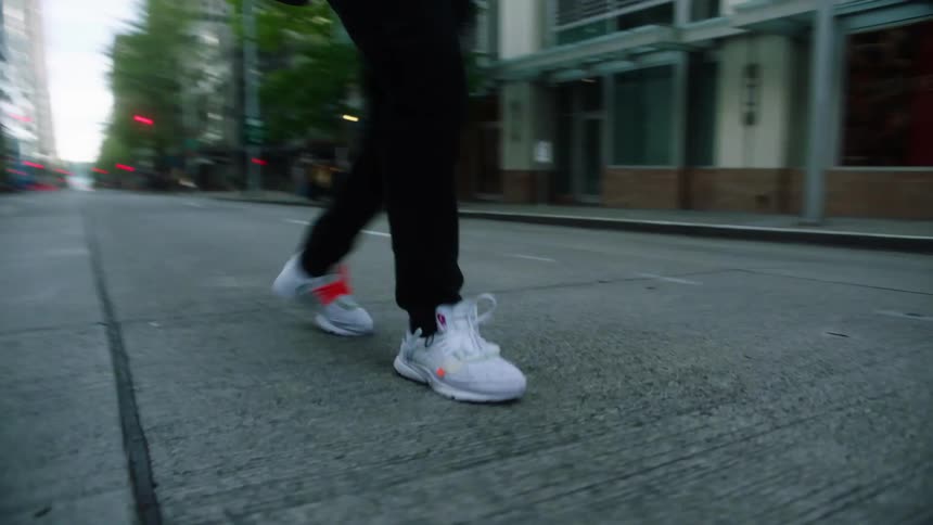Close up of a young man energetically dancing on the empty city streets at morning