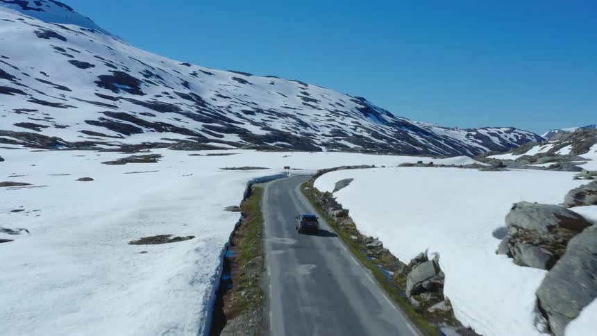 A car is driving down the road in the middle of the daytime