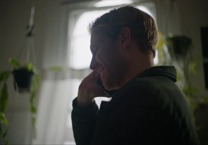 A man laughs while chatting on the phone
