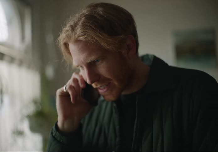 A man laughs while talking on his smartphone at home