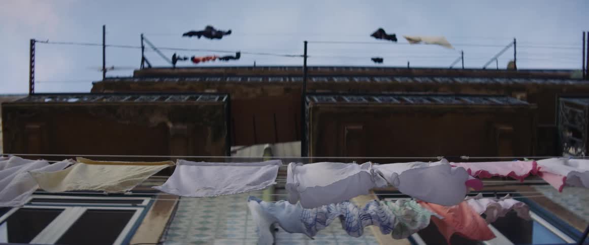 Clothes drying in the wind hanging from a balcony on the side of a building
