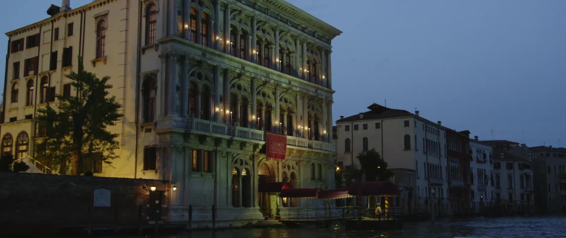 Low buildings seen from a moving boat on the river at nightfall