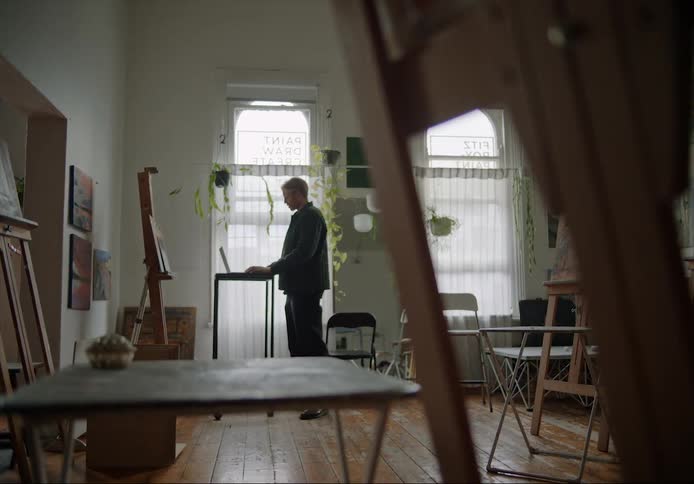 A man is standing in a room and typing on a laptop