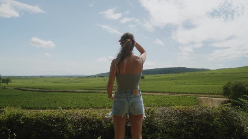 A woman is standing outside in the forest area and looking at the sky
