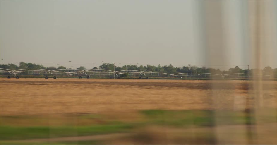 Cars are driving past a rural farm area at dusk
