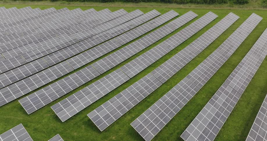 A myriad of solar panels are laying on flat grassy land