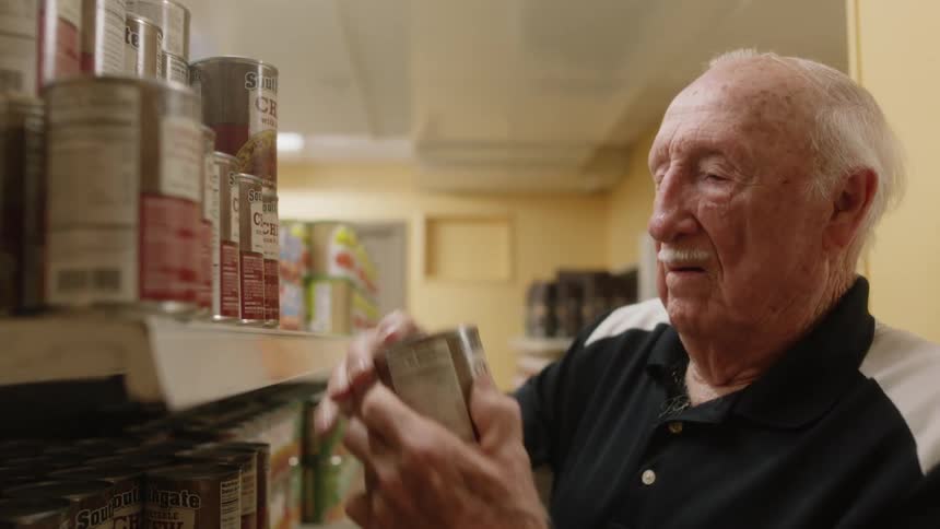 A man is putting cans on the shelves in a store