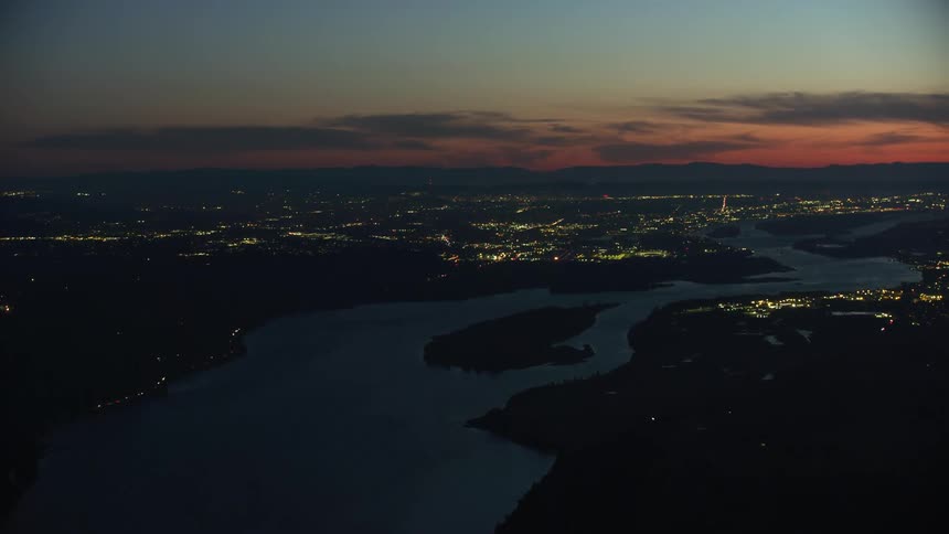 Night aerial time lapse flying into Portland down the Columbia River in stunning evening light and arriving airplanes can be seen flying through the evening sky in this aerial shot