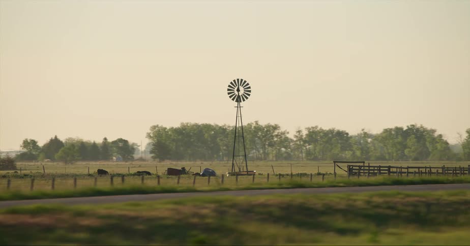 Windpump in the middle of a field on a farm close to the road at evening