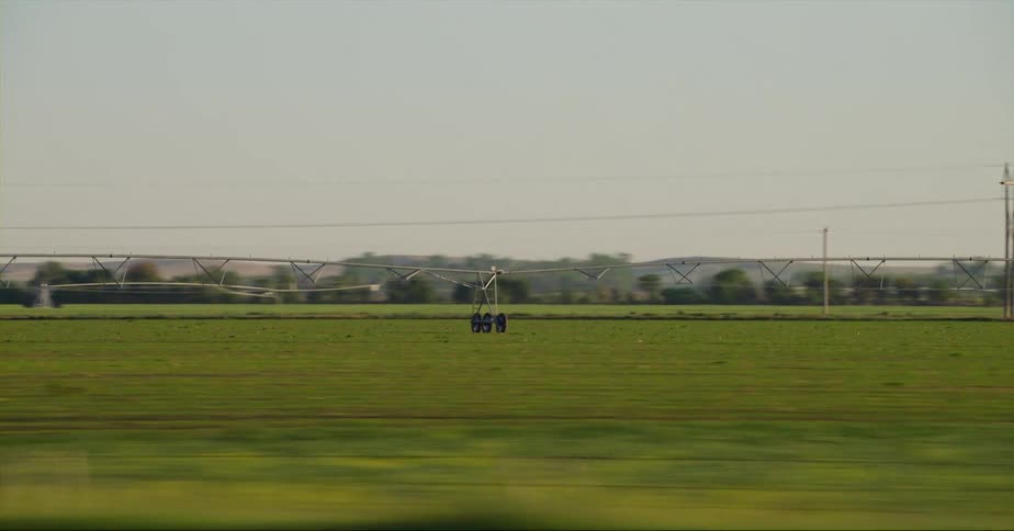 Cars are driving by a rural farm area during dusk