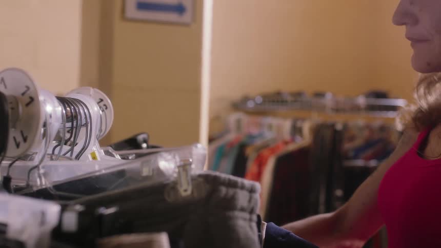 A woman is in a store shopping and taking clothes off of a rack to look at them