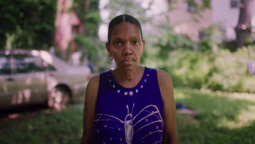 A woman is standing outdoors in her front yard