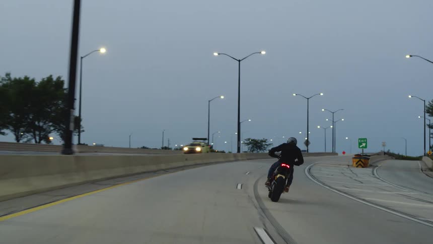 A person is driving a motorcycle on a highway during dusk