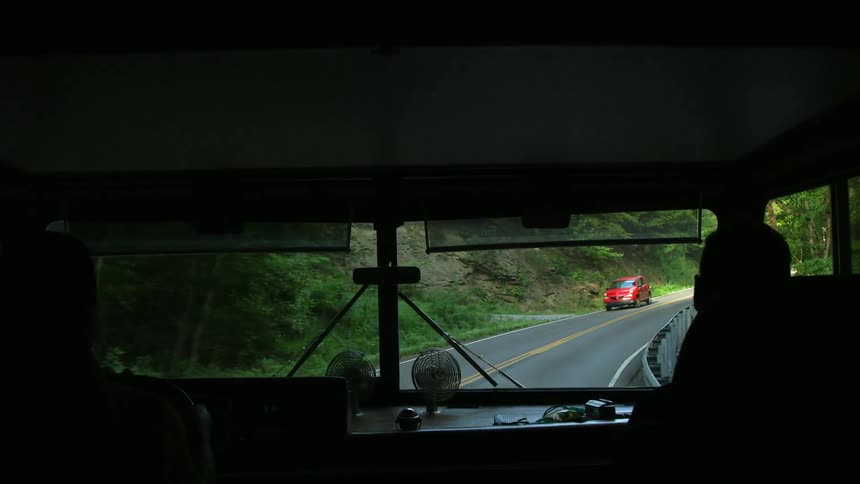 Driving down a two lane road as seen through the window of an rv