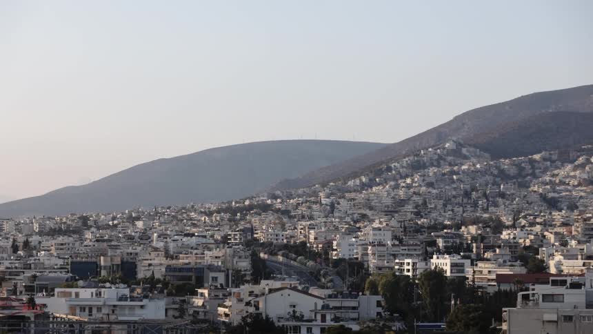 Apartment buildings and houses make up a dense neighborhood below rolling hills