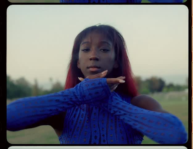 A woman moving her arms and hands around her face as she dances and poses