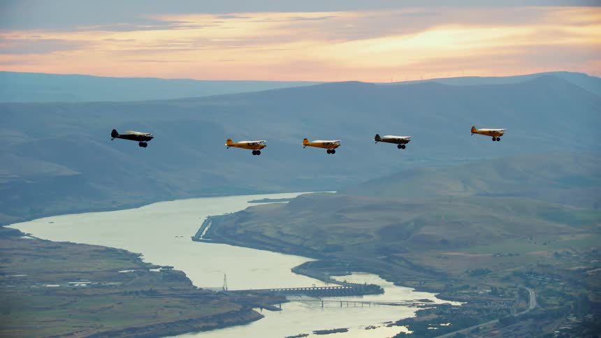 Light aircrafts fly over river at sunset