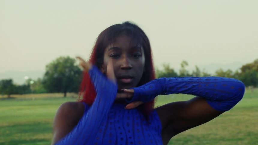 Female dancer wearing long fingerless gloves dances outdoors in field