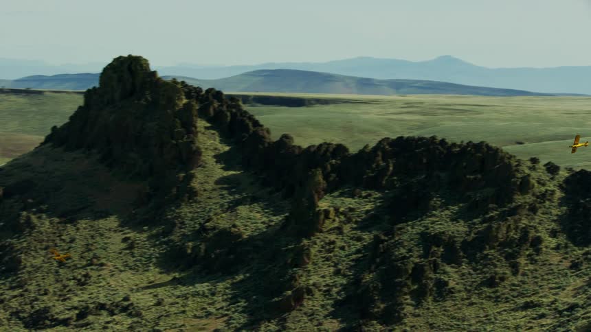 A group of small airplanes fly around a desert rock formation on the way into the backcountry