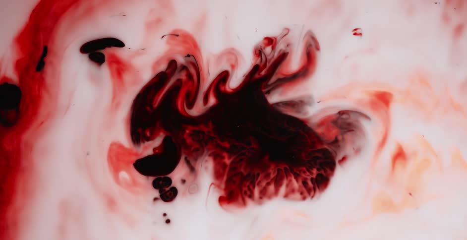 Red paint swirls in the middle of a pool of white paint and forms patterns