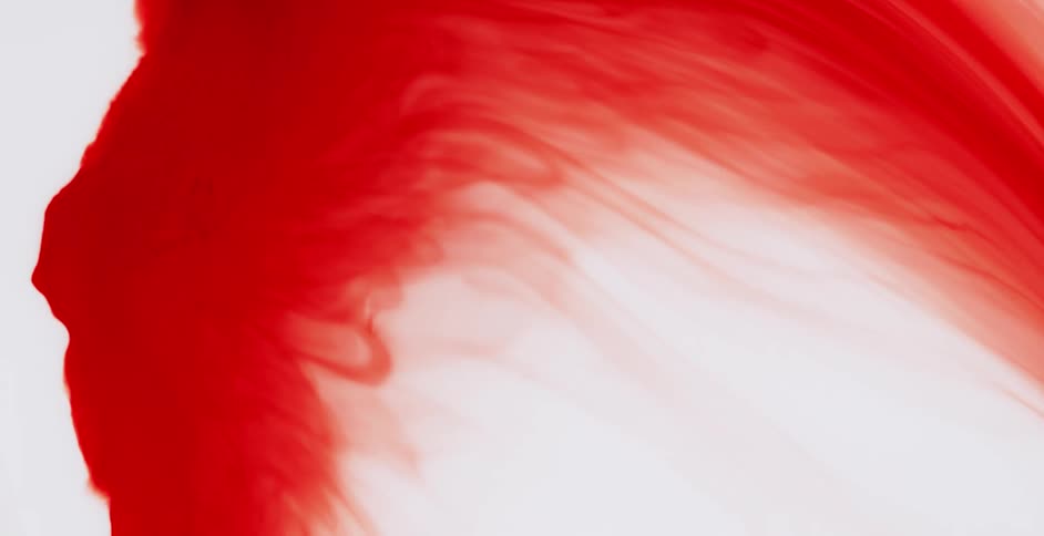 Red liquid is moving across white liquid and blending as it moves