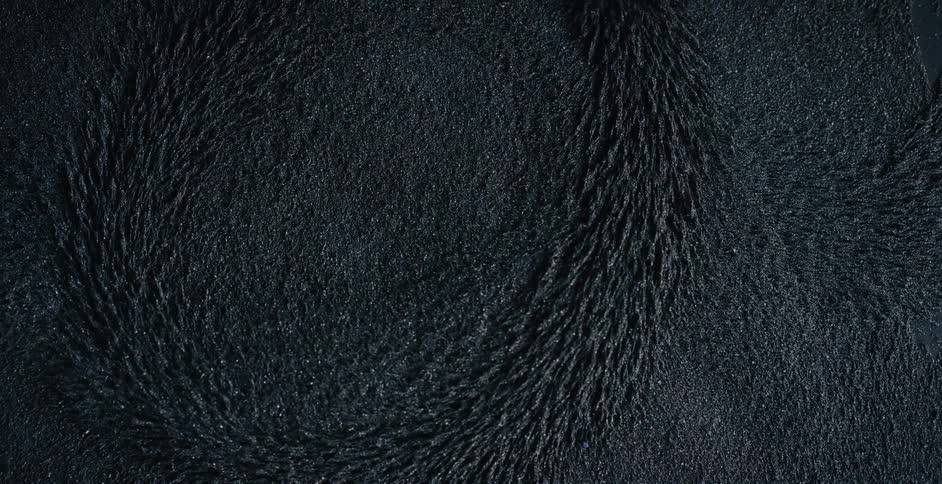 Iron dust on a dark room rises over the surface when a magnet moves underneath