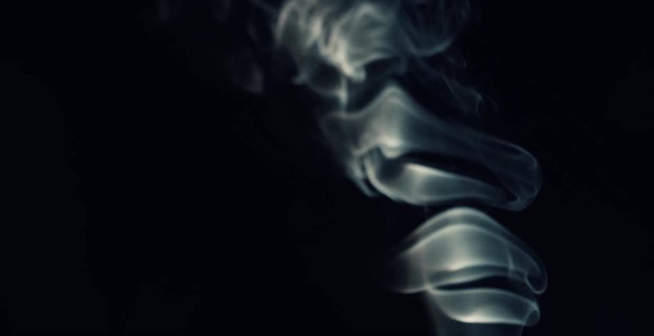 Waves of smoke float up in a ripple like pattern in the darkness
